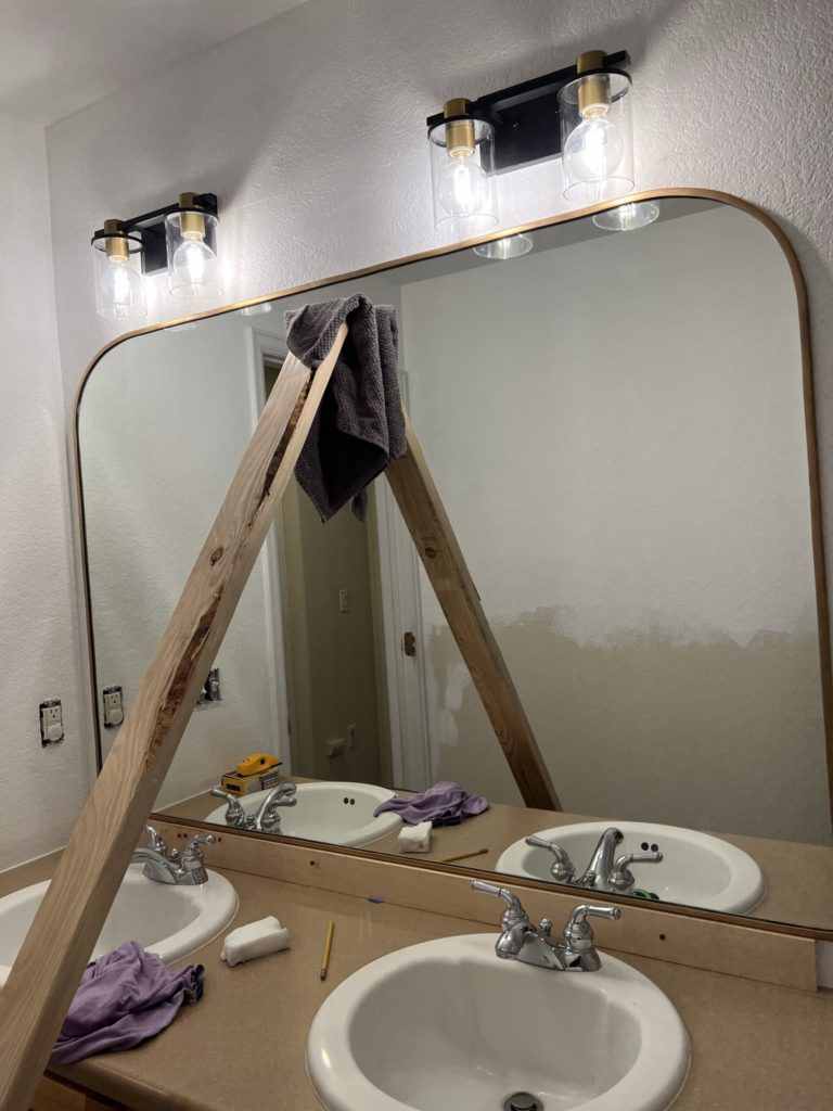 brace mirror with 2x4 while adhesive dries 